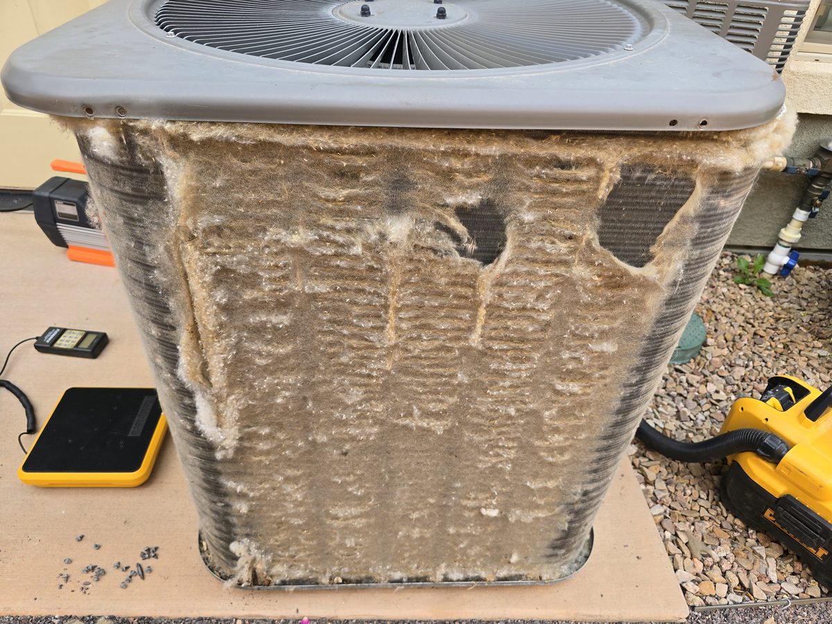 AC condenser coil clogged with cottonwood debris before cleaning